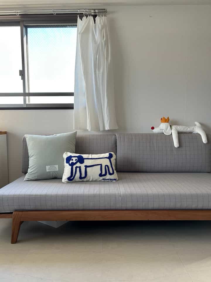 Bright and simple living room featuring gray check sofa with dog-themed cushions