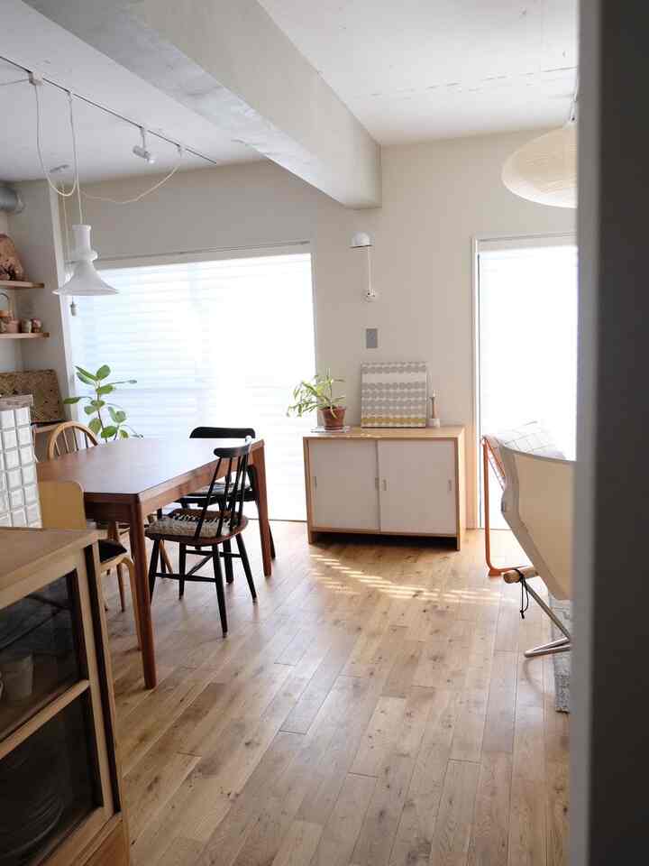 A natural color and wood tone Nordic living room featuring a dining table, storage cabinet, and various lighting fixtures in a cozy setting