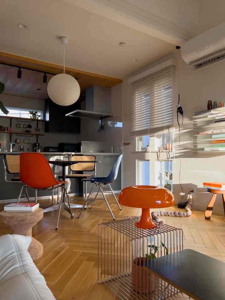 Modern dining room and kitchen featuring natural wood tones and orange accents with a cozy atmosphere