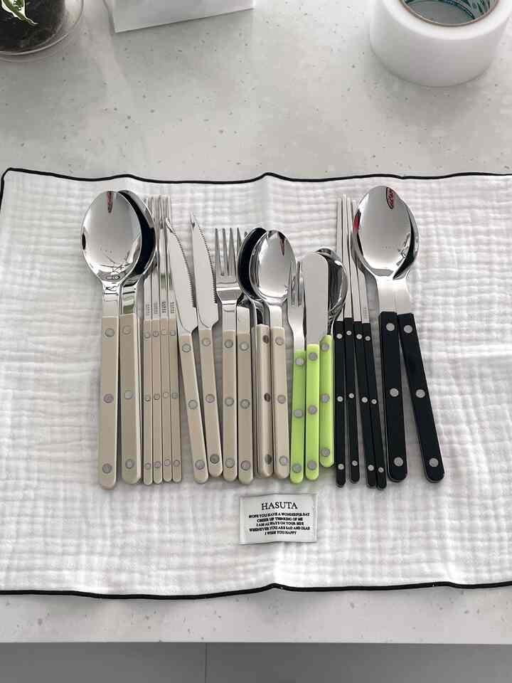 Modern kitchen utensils arranged neatly on a white background featuring SABRE cutlery in various colors