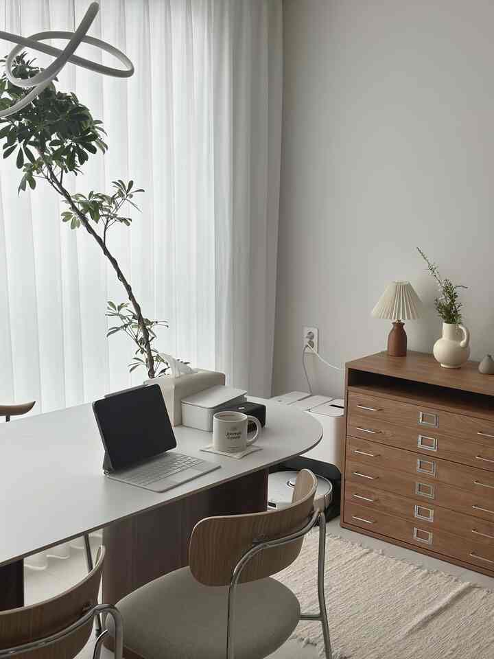 白と木目調の調和があるリビング兼ワークスペース、デスクとチェストがすっきり配置された落ち着いた雰囲気のインテリア