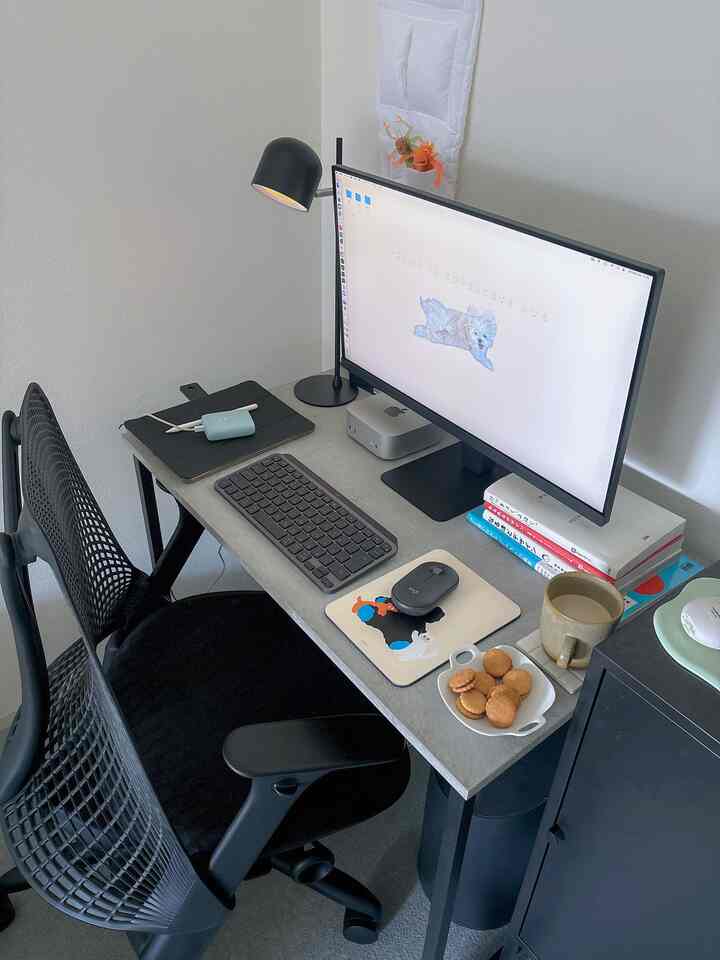 グレー調のコンパクトな一人暮らしのホームオフィス、黒のオフィスチェアとデスク、モニター、本がシンプルに配置されたミニマルな雰囲気のインテリア