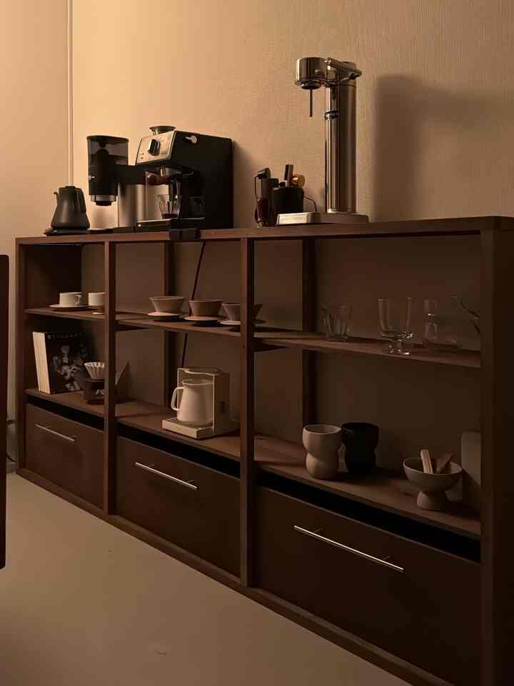 温かみのあるブラウンの棚が並び、コーヒー器具やカップが整然と配置された落ち着いた雰囲気のホームカフェインテリア