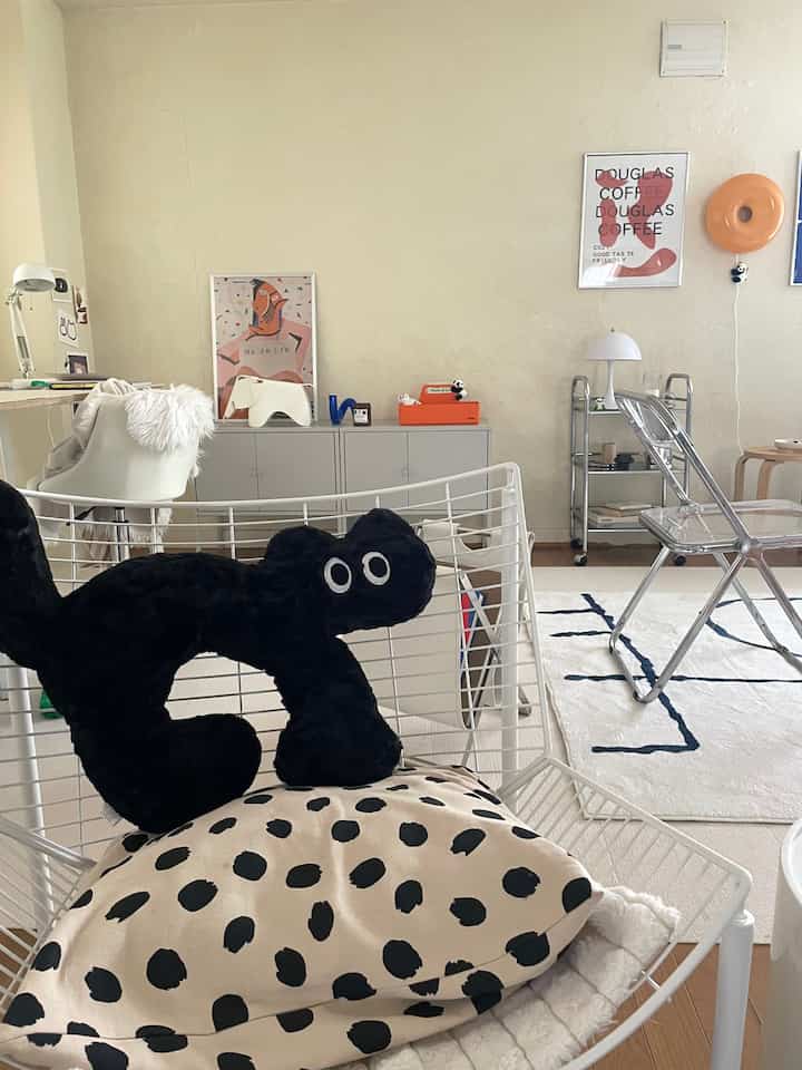 ホワイトとウッドトーンの1DKリビング、動物モチーフのクッションやインテリア小物が配置された雰囲気のある空間