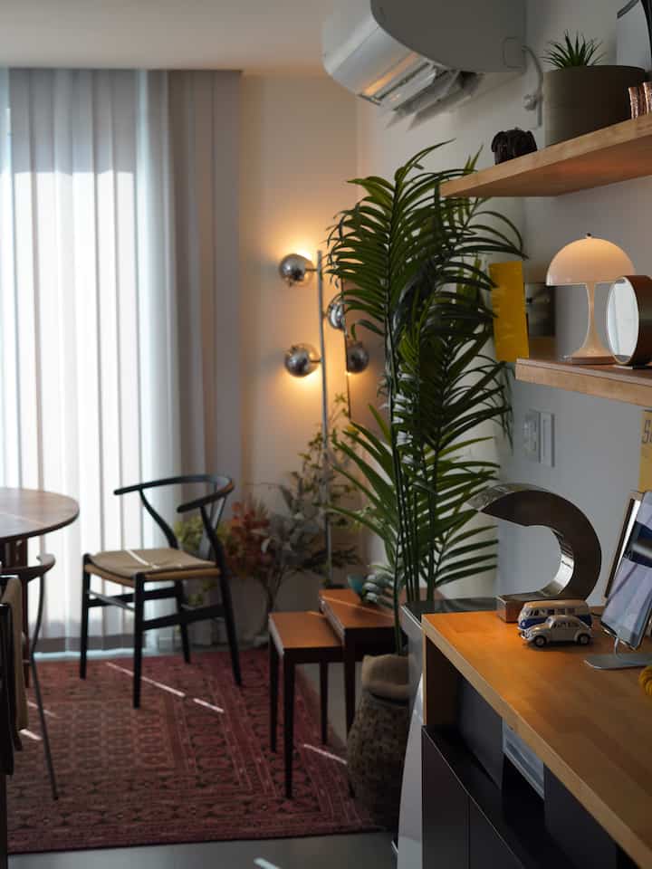 Brown wood tones and green fake plants in a Nordic dining room featuring indirect and table lighting creating a cozy atmosphere