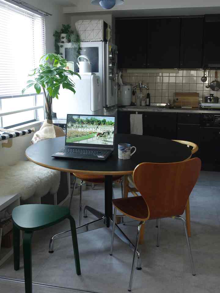 ナチュラルカラーと黒を基調とした1LDKのダイニング、丸いダイニングテーブルと椅子が配置された雰囲気のある空間