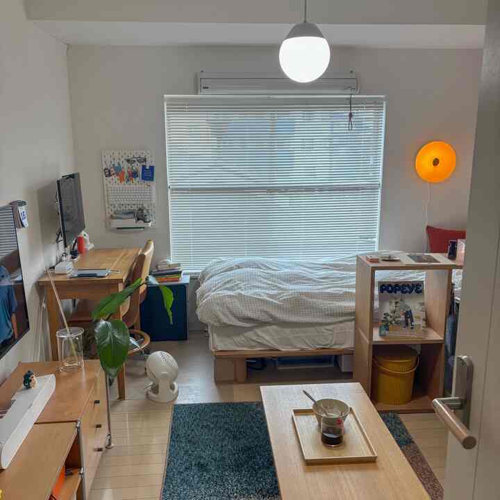 白い壁と木目調家具が調和した7畳の寝室、デスクとベッドが配置されたナチュラルな一人暮らし空間