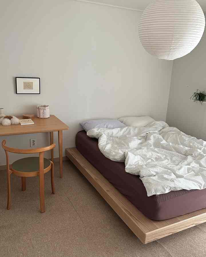 白と木目調の寝室、低い木製ベッドとデスクが配置された落ち着いたナチュラルな空間