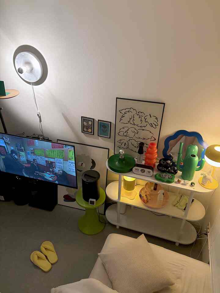 暖かいベージュ調の一人暮らし用寝室、壁照明と棚の上にかわいい雑貨が配置された居心地の良い空間