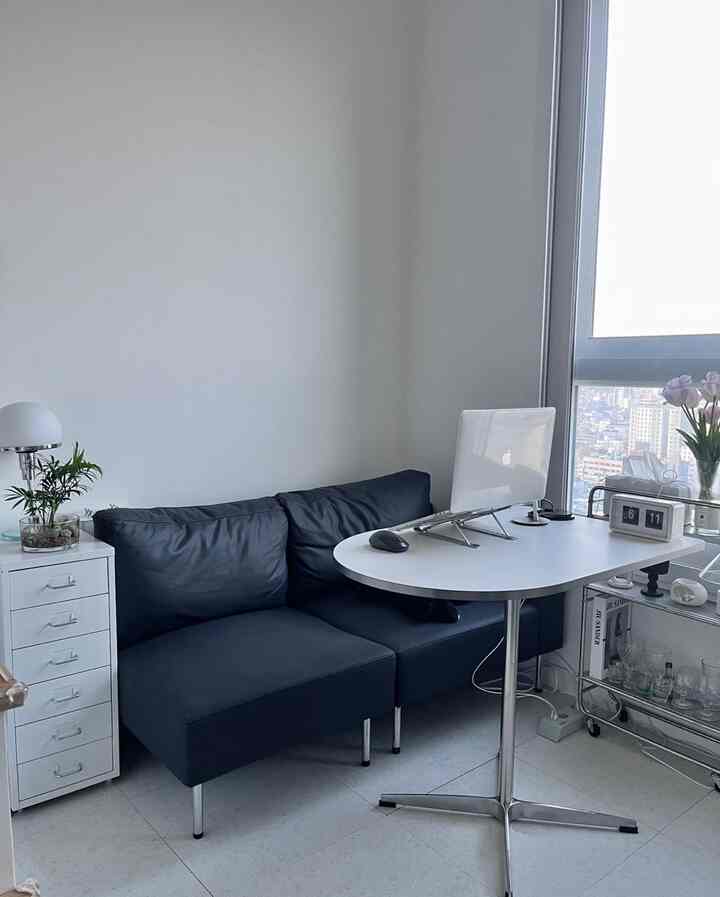 白とネイビーカラーのワンルームホームオフィス、ソファとデスク、ドレッサーが配置された落ち着いた空間