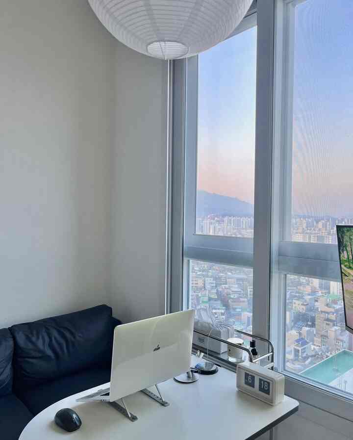 白とネイビーのトーンのホームオフィス、ノートパソコンのあるデスクとソファが配置されたモダンで清潔感のあるインテリア