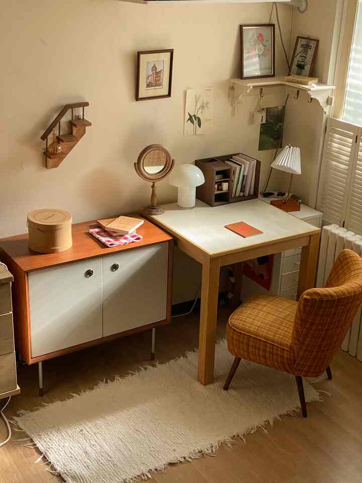 ナチュラルな木目調とミッドセンチュリーモダンスタイルの寝室、デスクとオレンジ柄のアームチェア、壁の額縁が温かみのある雰囲気を演出