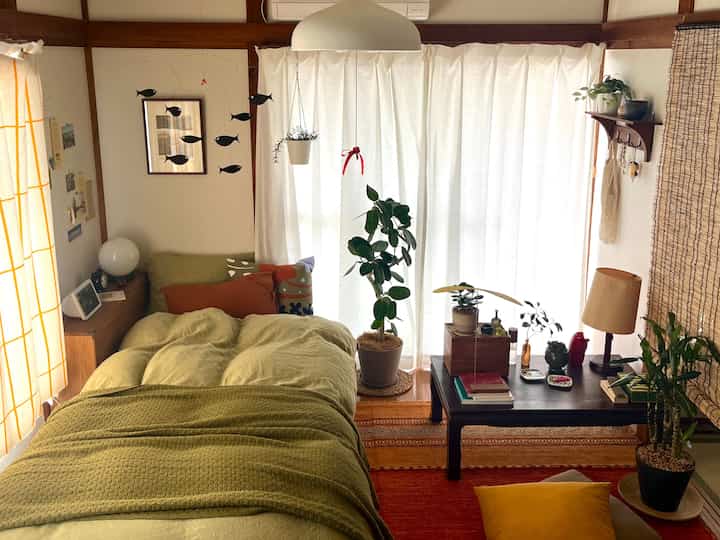 Beige and green toned serene bedroom featuring multiple plants and wooden furniture with a cozy atmosphere