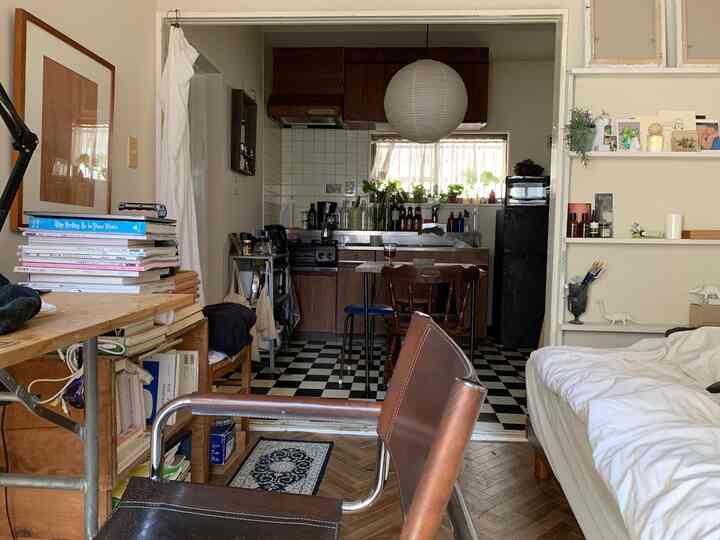 White and brown toned studio apartment featuring kitchen, bed, desk, and chairs creating a natural modern atmosphere