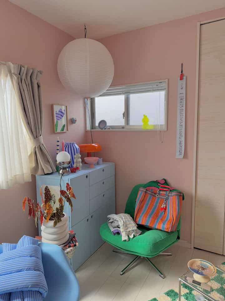 Pastel pink-walled 6-tatami room with a green armchair and colorful accessories, creating a bright and cozy atmosphere