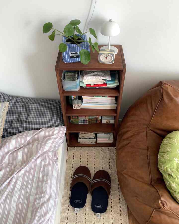 白い壁と茶色の家具が調和した小さな部屋、ビーンバッグソファと収納棚が配置された落ち着いた空間