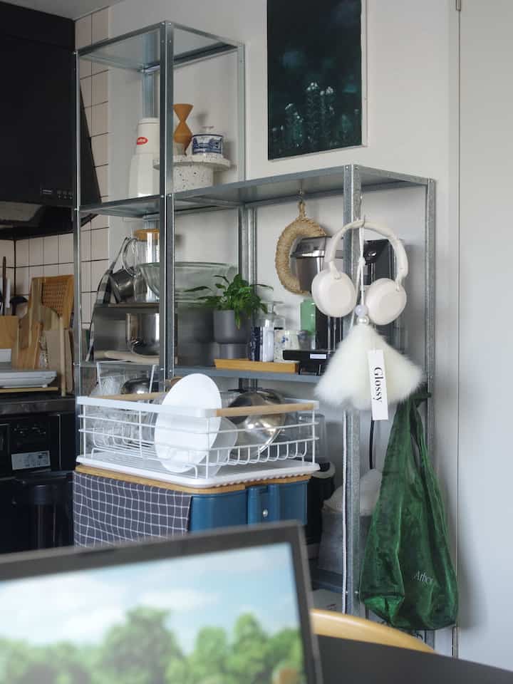 白い壁を背景にメタル棚が印象的な一人暮らしのキッチン、整頓された食器と調理器具が配置された雰囲気のあるインテリア