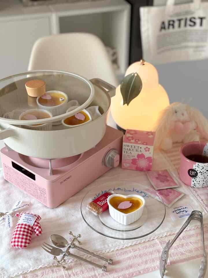 パステルカラーの温かい照明がある可愛らしいキッチンテーブル、ハート形のデザートとお茶が置かれた雰囲気のあるおうちカフェ空間