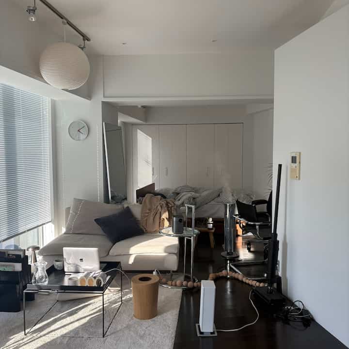 暖かい日差しが差し込む白とベージュのモダンなリビング、ベージュのソファとコーヒーテーブルが配置された落ち着いた空間