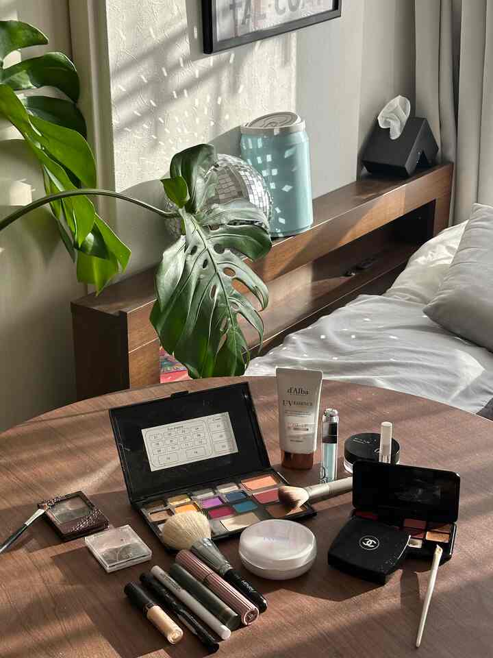 温かみのある木目調の小さな寝室、丸いダイニングテーブルの上にメイク道具と植物が置かれた雰囲気のあるインテリア