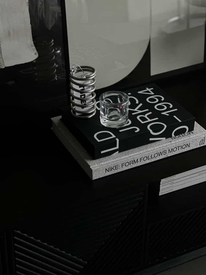 Dark black-toned table surface featuring a silver stainless steel spiral holder and transparent glass candle holder in a sleek decor arrangement