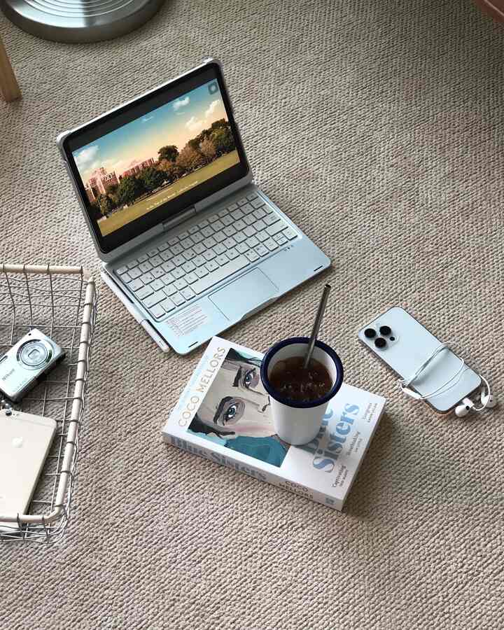 ベージュのカーペットの上にノートパソコンと本、飲み物が置かれたナチュラルモダンな印象のホームオフィス空間