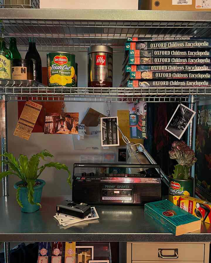 金属製の棚にレトロな小物が置かれた作業スペース、彩り豊かなオブジェで飾られた雰囲気のあるインテリア