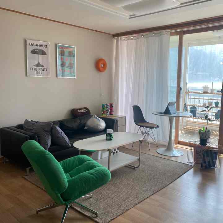 白と黒のトーンが調和した3人暮らし用リビング、ミッドセンチュリーモダンのソファとアームチェア、明るい自然光が差し込むバルコニーを含む印象的な空間