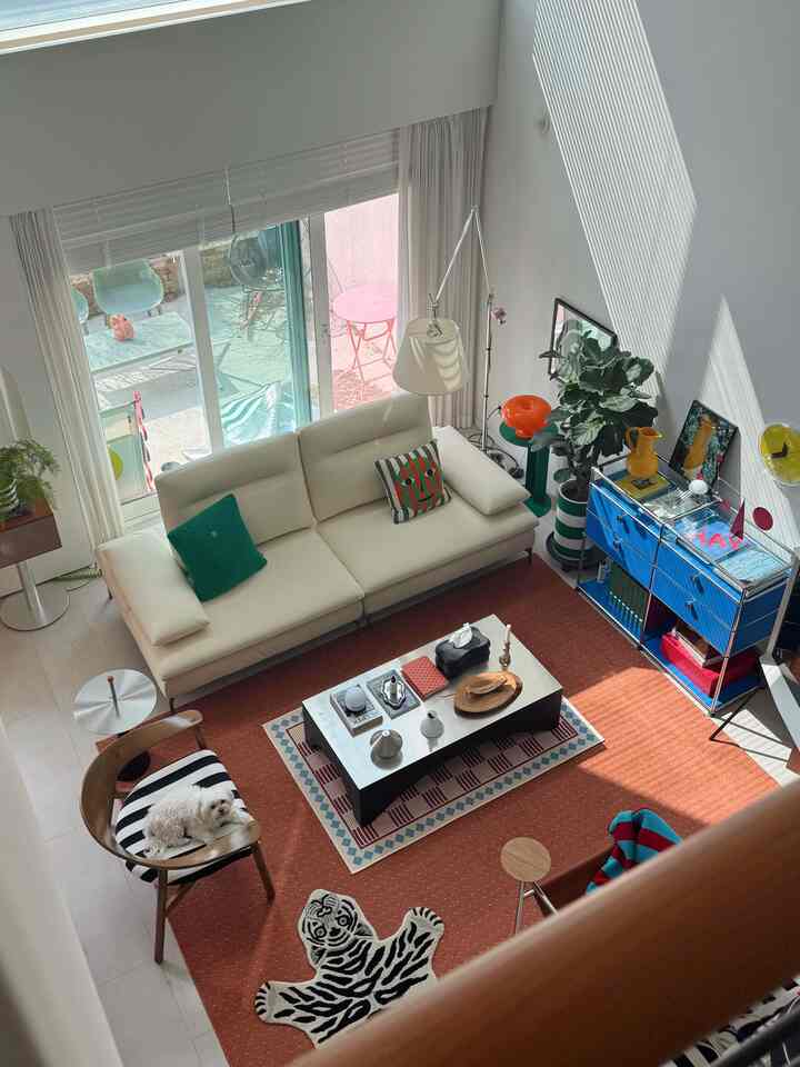 Bright natural-tone living room featuring a white sofa, red rug, and a dog resting on a black-striped chair