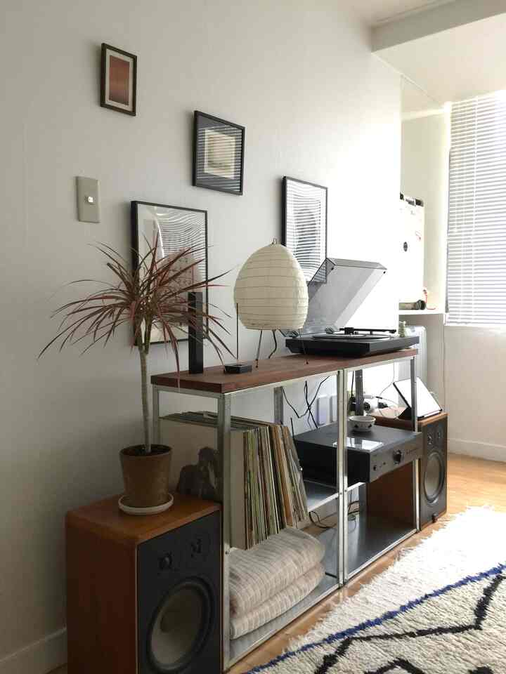 自然なウッドトーンとナチュラルカラーのリビング、LPプレーヤーとターンテーブル、植物と額縁が調和するヴィンテージスタイルのインテリア
