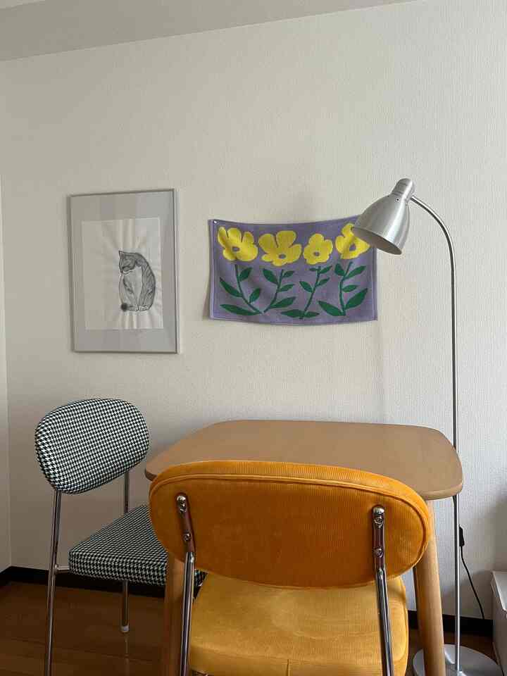 Natural-colored dining room featuring a yellow chair, patterned chair, wooden dining table, and silver floor lamp with a clean atmosphere