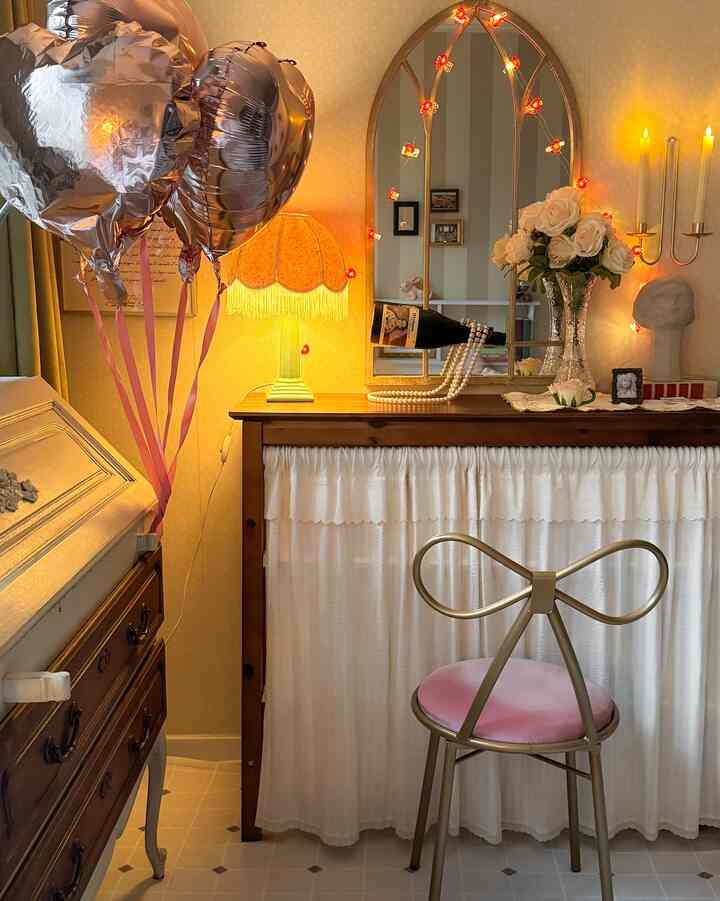 暖かいブラウンとイエローのトーンのフレンチカントリー空間、アーチ型の鏡とピンクのリボンチェアが配置された印象的なインテリア