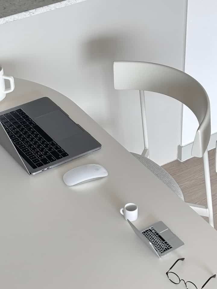 White and natural tone dining table and chairs arranged in a clean home office and dining area