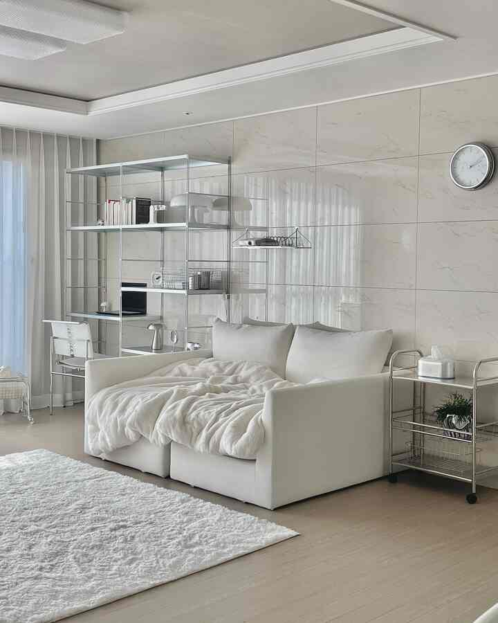 ホワイトとシルバーの色調のリビング、モダンなソファとオープンシェルフが配置された清潔感のある空間