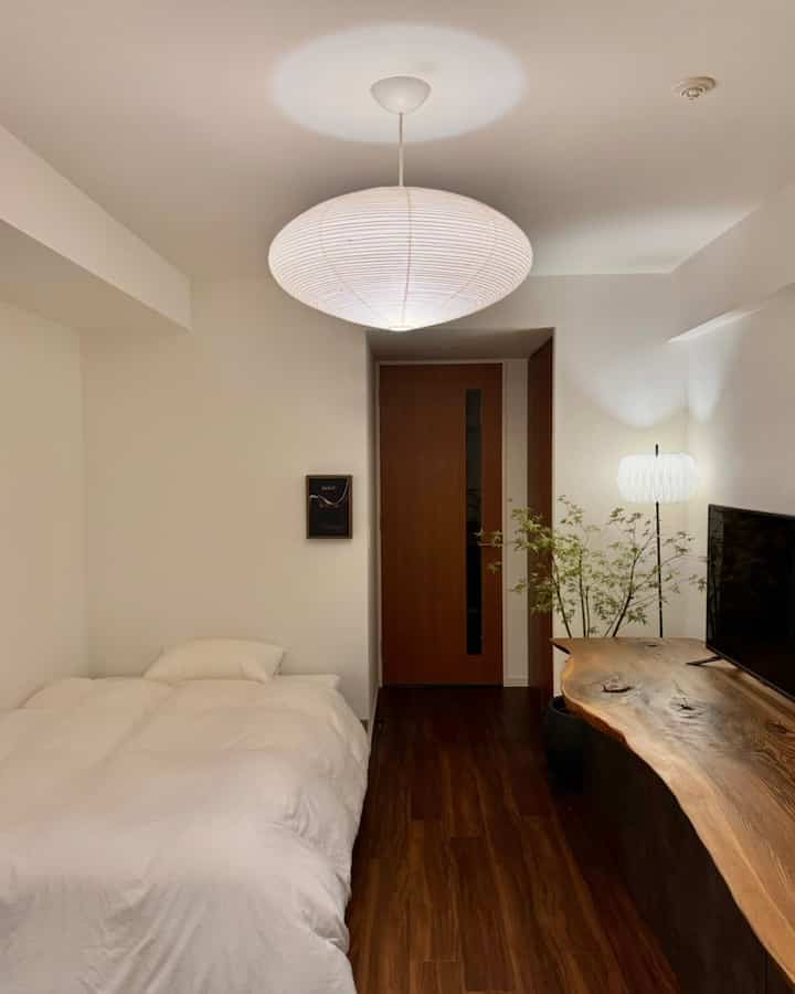 白と木目調が調和する一人暮らしの寝室、アカリ21Aのペンダントライトが雰囲気を演出するナチュラルな印象的な空間