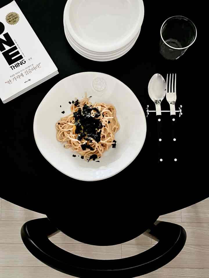 Modern simple dining space featuring a black round table with white plates, bowl, and cutlery neatly arranged