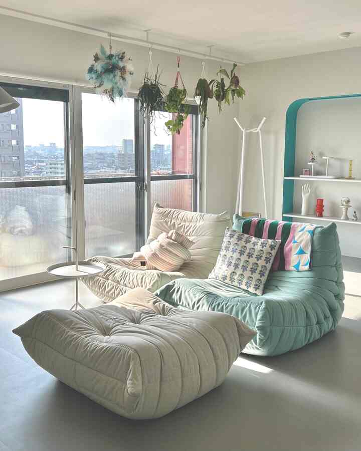 明るくナチュラルなリビングルーム、ライトグレーの床とミント色のソファ、バルコニーの窓と吊り下げた植物が調和する空間