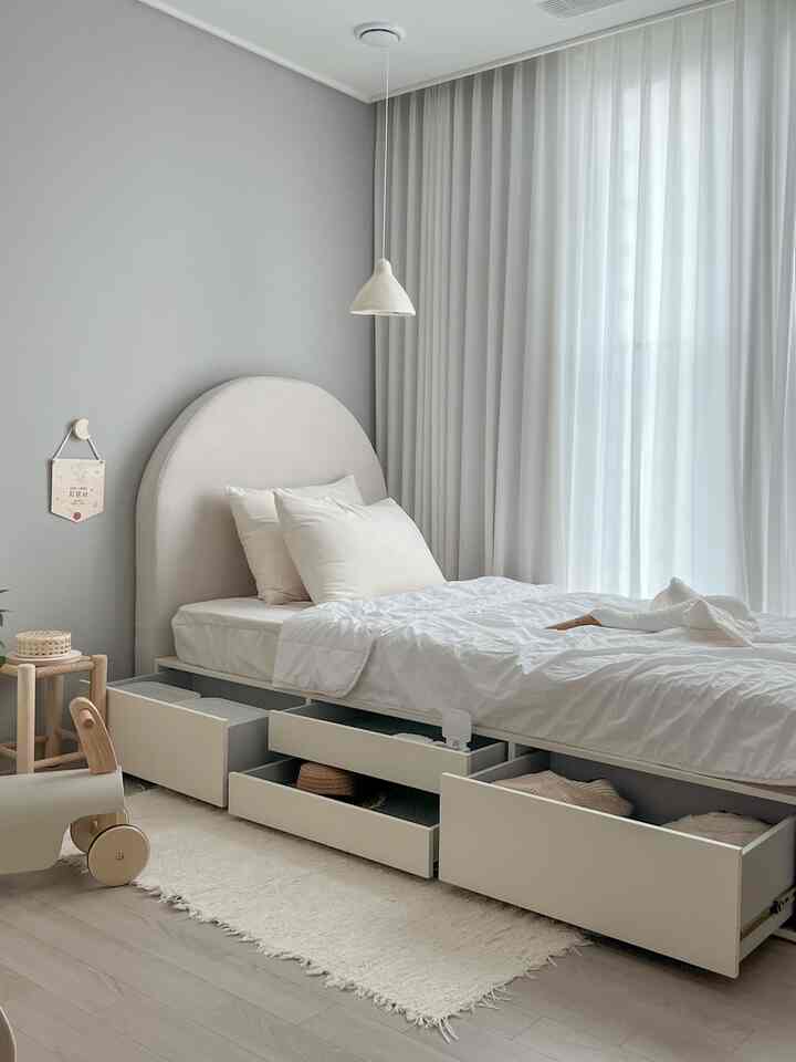 ベージュとグレーの色調の子供部屋、収納付きベッドと白いカーテンが配置された自然でミニマルな雰囲気のあるインテリア