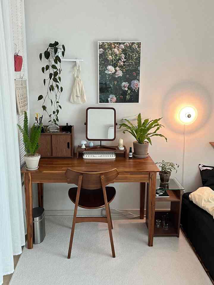 木目調の家具と壁付け照明、植物が配置されたシンプルなワンルームのデスクスペース