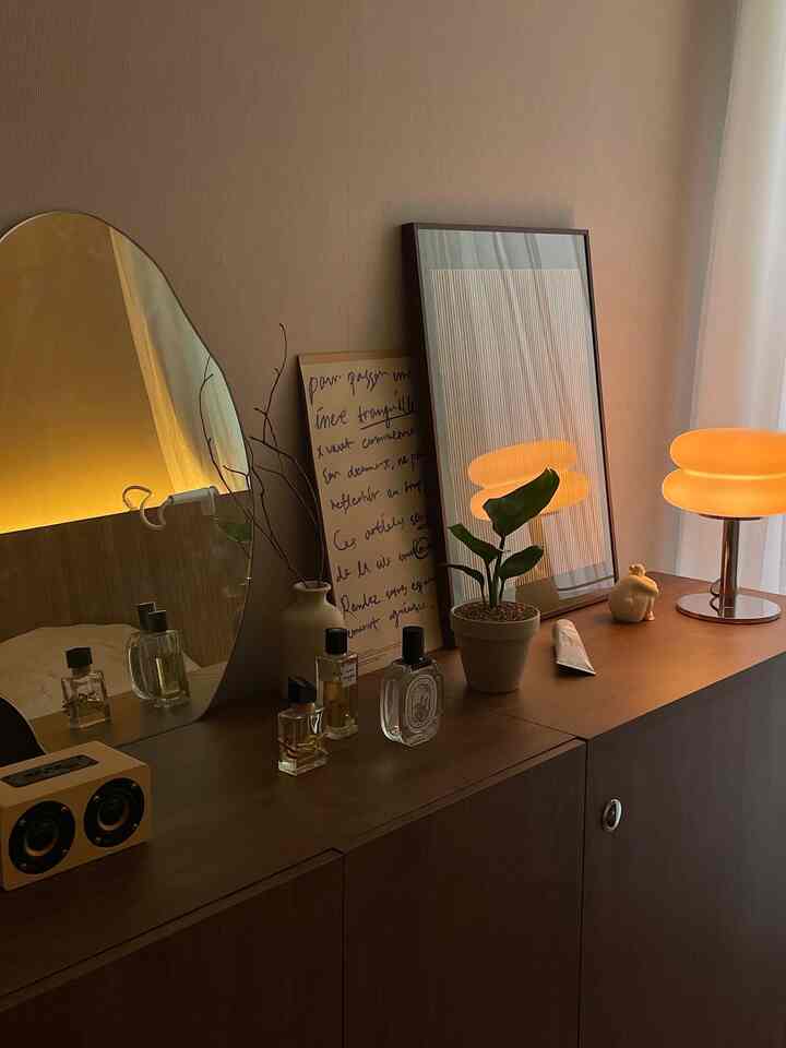 暖かいブラウン調の寝室、収納キャビネットの上にオブジェや照明が配置された雰囲気のある空間