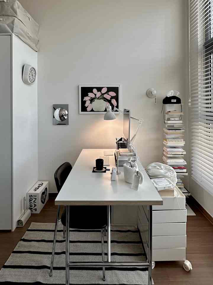 白と黒のトーンでまとめられたワンルームのホームオフィス、ミッドセンチュリーモダンスタイルのデスク、椅子、照明、本棚が配置された印象的な空間