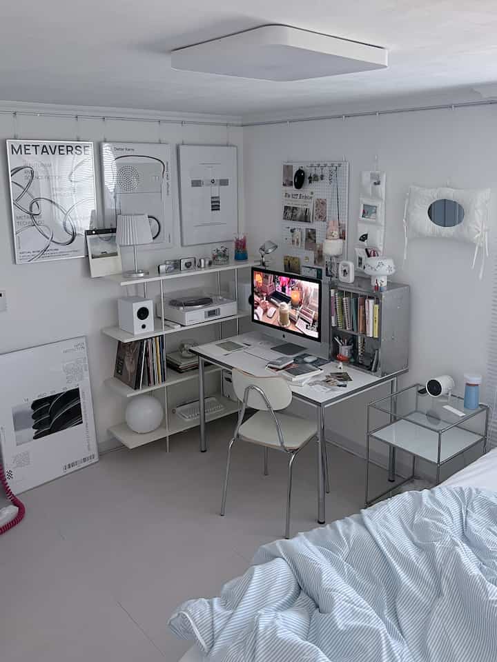 A modern small room (~9.9 sqm) with white and gray tones featuring a clean desk, chair, bookshelf, and desk décor elements