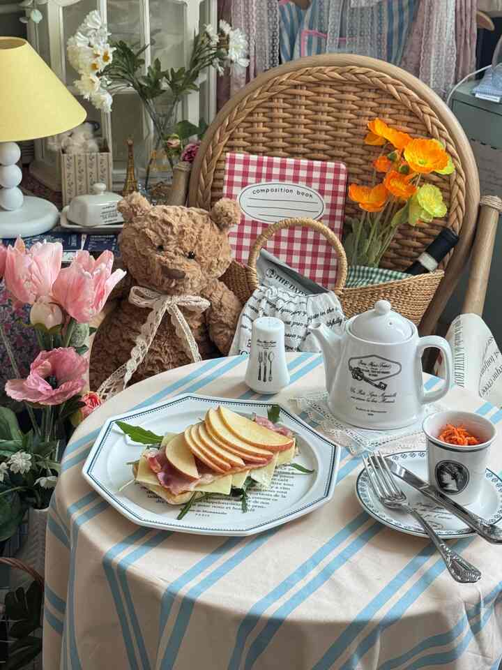 ベージュとナチュラルカラーのカフェ風インテリア、ラタンチェアと花、ティーポットが配置された雰囲気のある空間