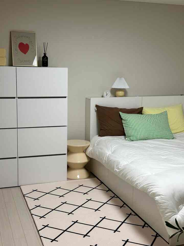 白とベージュのトーンの寝室、チェストとナイトテーブルが配置されたシンプルで整ったインテリア