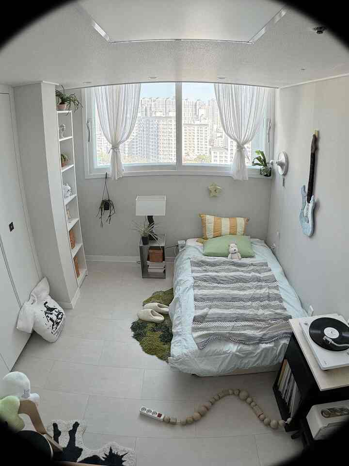 白と緑の色調のワンルーム寝室、ベッド、書棚、カーテンが配置されたミッドセンチュリーモダンの印象的な空間