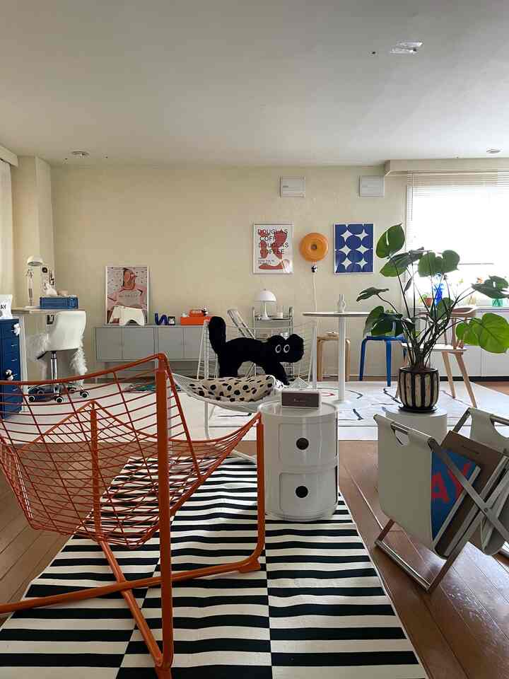 Monotone black and white 1DK living room featuring a striped rug, cat cushion, orange armchair, and Nordic Mid-Century Modern decor.