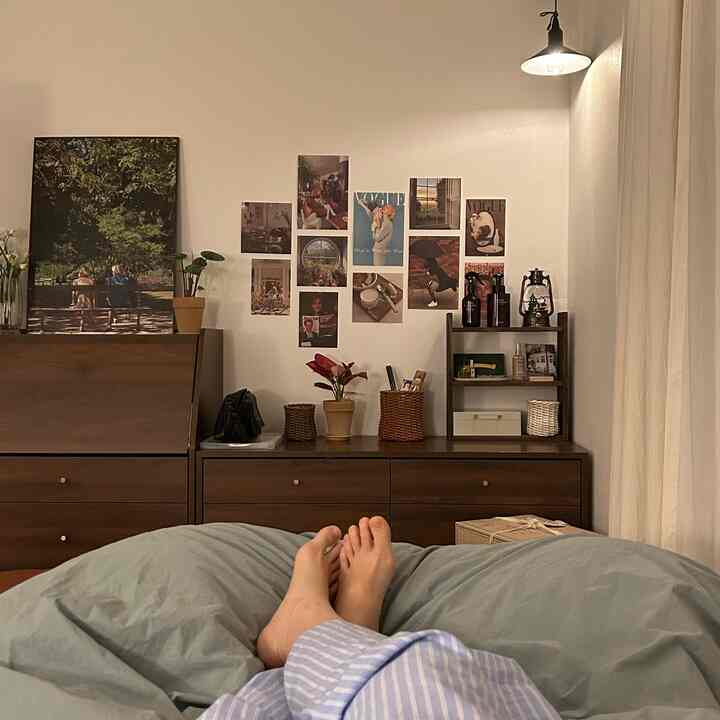 ブラウンとアイボリーのトーンが特徴のワンルーム寝室、ドレッサーと壁に配置された額縁が印象的な雰囲気のあるインテリア