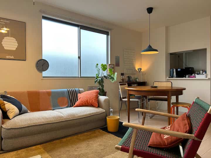 Natural-toned wide living room featuring wooden dining table and cozy sofa in a simple setting