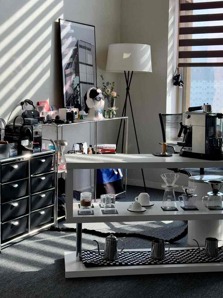 ホワイトとブラックのモノトーンのホームカフェ兼ホームオフィス空間、照明と植物が配置されたミッドセンチュリーモダンのインテリア