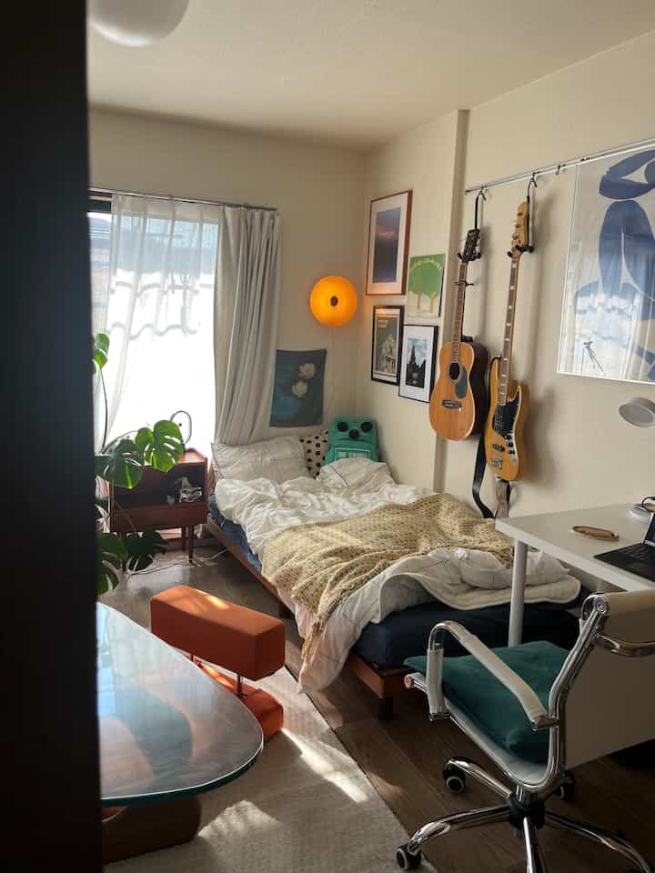 白と茶色のトーンの8畳寝室、木製家具と観葉植物が配置された落ち着いた一人暮らし空間